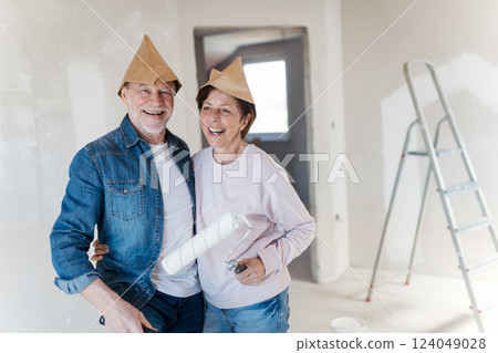 Portrait of senior couple having fun while painting walls with roller in new home. 124049028