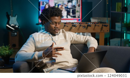 Responsible male adult does his taxes with the credit card at home, entering numbers online on laptop and confirming the payment via web. Man organizing documents and financial details. Camera A. 124049031