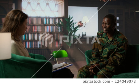Counselor offering support to war veteran during therapy session, suffering from bipolar disorder and shell shock. Distraught serviceman dealing with war flashbacks, traumatic experiences. Camera A. 124049078