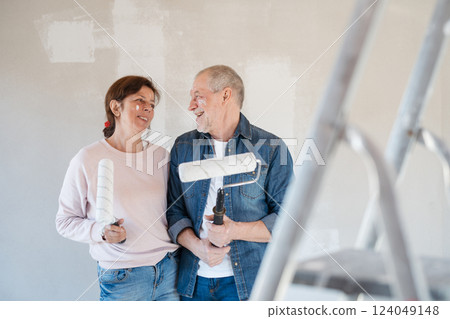 Portrait of senior couple painting walls with roller in new home. 124049148