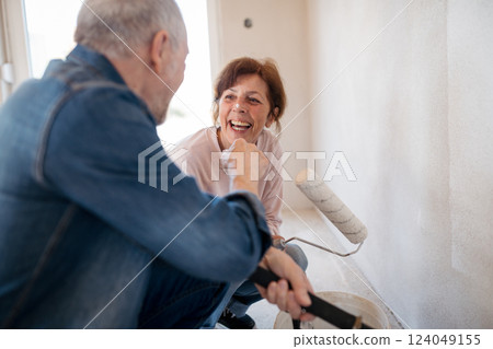Senior husband and wife repainting the walls. 124049155