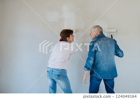 Senior husband and wife repainting the walls. 124049164
