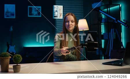 Focus on smartphone used by content creator in blurry background to film room tour. Close up of mobile phone used by teenage entertainer doing video presenting apartment to fans, camera B Focus on smartphone used by content creator in blurry background to film room tour. Close up of mobile phone used by teenage entertainer doing video presenting apartment to fans, camera B 124049266