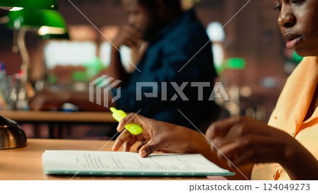 African american scholar highlighting the relevant information from class notes, creating a summary with highlighter pen. Student underlining key words and phrases from the course. Camera B. African american scholar highlighting the relevant information from class notes, creating a summary with highlighter pen. Student underlining key words and phrases from the course. Camera B. 124049273