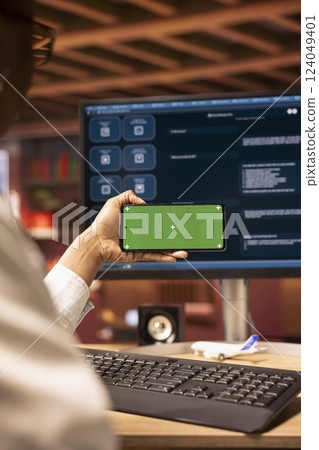 Woman using isolated screen mobile phone to look at video tutorials about AI chatbots, closeup. Person holding chroma key smartphone to look at visual guides on artificial intelligence LLMs 124049401