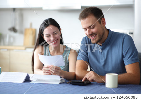Happy interracial couple calculating expenses uisng calculator Happy interracial couple calculating expenses uisng calculator 124050083