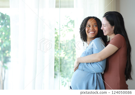Happy pregnant lesbian woman looking at her girlfriend at home 124050086