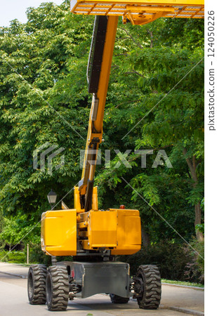 High yellow lift crane with platform for garden works, trees care. Cutting tree on a high. Hydraulic ramp. Remove branches and twig. Gardening work. High yellow lift crane with platform for garden works, trees care. Cutting tree on a high. Hydraulic ramp. Remove branches and twig. Gardening work. 124050226