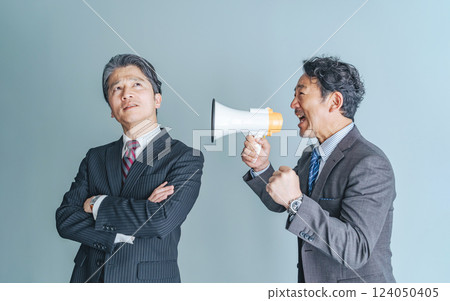 A middle-aged male business person calling out to a thoughtful middle-aged man through a loudspeaker 124050405