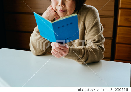 A senior woman resting her chin on her hand and looking at her pension book A senior woman resting her chin on her hand and looking at her pension book 124050516