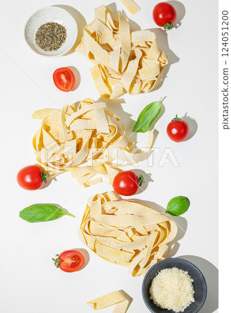 Flat-lay of fresh pasta with tomatoes and basil on white background. 124051200