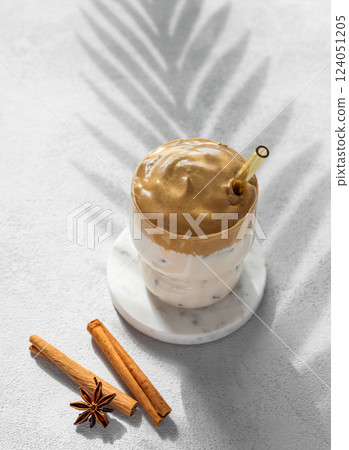 Korean whipped drink Dalgona coffee on a light background with spice and palm leaf shadow. Korean whipped drink Dalgona coffee on a light background with spice and palm leaf shadow. 124051205
