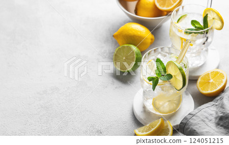 Two glasses of mojito cocktail with fresh lemon, lime, mint and ice on a light background  124051215