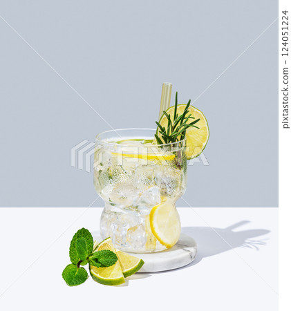 Refreshing mojito with lime, lemon, rosemary and ice in a glass on a white blue background  124051224