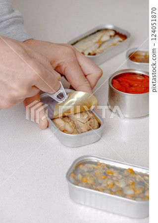 man opening a can of frigate tuna fillets man opening a can of frigate tuna fillets 124051870