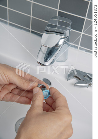 man disassembles a sink faucet aerator man disassembles a sink faucet aerator 124051872