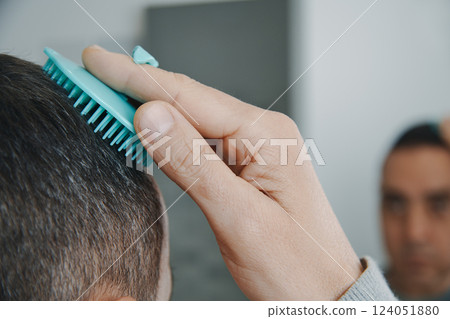 man combs his hair in the bathroom man combs his hair in the bathroom 124051880