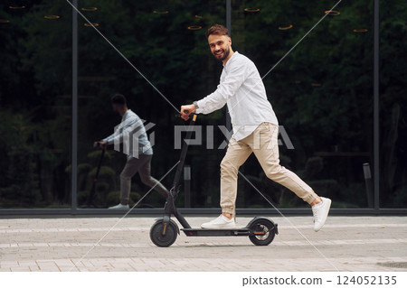 Riding the scooter. Stylish man is outdoors at daytime 124052135