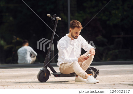 Sitting on the scooter. Stylish man is outdoors at daytime Sitting on the scooter. Stylish man is outdoors at daytime 124052137