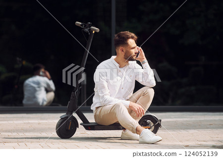 Sitting on the scooter. Stylish man is outdoors at daytime 124052139