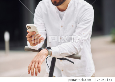 Close up view. Stylish man is with his scooter outdoors at daytime 124052154