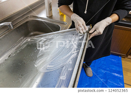 The hands of a person removing a glass window and washing it with detergent 124052365