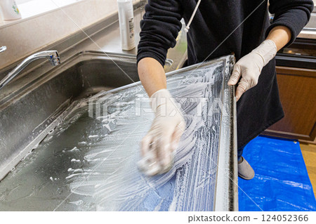 The hands of a person removing a glass window and washing it with detergent 124052366