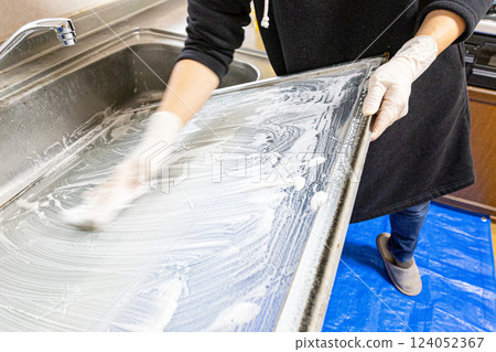 The hands of a person removing a glass window and washing it with detergent 124052367