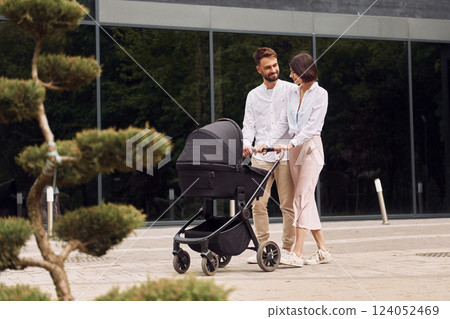 Conception of love. Young parents having a walk with baby carriage outdoors Conception of love. Young parents having a walk with baby carriage outdoors 124052469