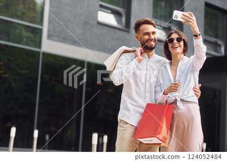 Making selfie. Beautiful couple have a shopping day outdoors at daytime 124052484