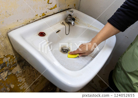 A woman's hands cleaning an old washbasin with a sponge A woman's hands cleaning an old washbasin with a sponge 124052655