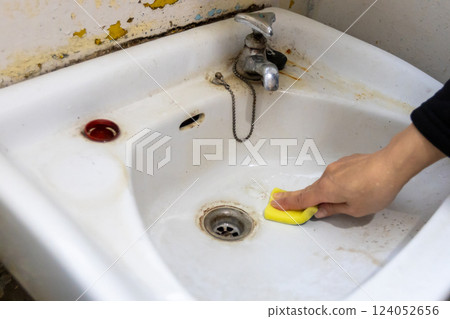 A woman's hands cleaning an old washbasin with a sponge A woman's hands cleaning an old washbasin with a sponge 124052656