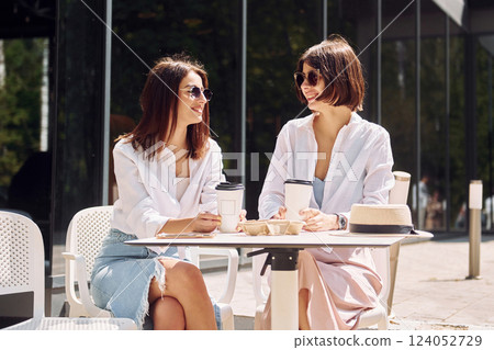 At sunny daytime. Two female friends have great weekend outdoors together At sunny daytime. Two female friends have great weekend outdoors together 124052729