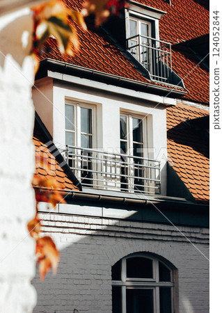 Building balcony, white brick facade and brown roof. Apartment building with balcony. Fall season in the city. Urban real estate European architecture Building balcony, white brick facade and brown roof. Apartment building with balcony. Fall season in the city. Urban real estate European architecture 124052844