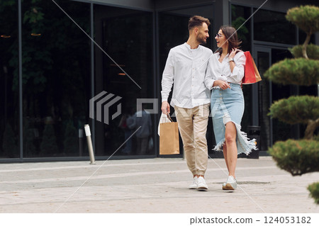 Walking near modern building. Beautiful couple have a shopping day outdoors at daytime Walking near modern building. Beautiful couple have a shopping day outdoors at daytime 124053182