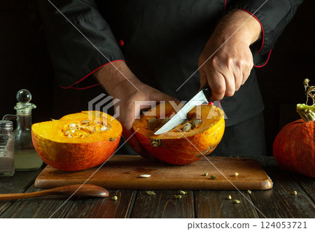 Cutting a ripe big watermelon with a knife in the hands of a skilled chef. Low key concept of cooking a national dish on the kitchen table. 124053721