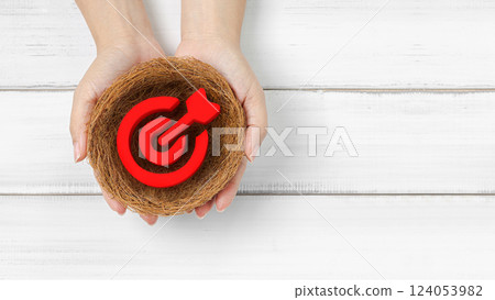 Target Achievement: Hands Holding a Red Bullseye Symbol in a Nest 124053982