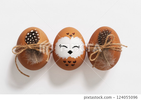 Easter egg in the design of a sleeping owl. Easter eggs with feathers and twine. 124055096