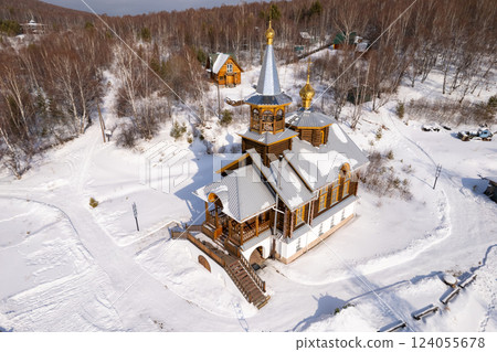 Aerial top view to wooden church of Transfiguration covered snow of the Lord on mountain near village Port Baikal. Frozen ice Lake and river Angara on backgroud. Winter landscape Siberia, Russia. Aerial top view to wooden church of Transfiguration covered snow of the Lord on mountain near village Port Baikal. Frozen ice Lake and river Angara on backgroud. Winter landscape Siberia, Russia. 124055678