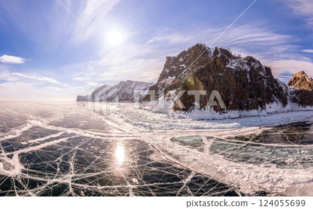 Aerial top view to Blue clear ice Cape Khoboy lake Baikal. Crack covered snow on frozen water surface. Cold winter landscape in sunny day, Natural background. Small Sea, Olkhon, Siberia, Russia. Aerial top view to Blue clear ice Cape Khoboy lake Baikal. Crack covered snow on frozen water surface. Cold winter landscape in sunny day, Natural background. Small Sea, Olkhon, Siberia, Russia. 124055699