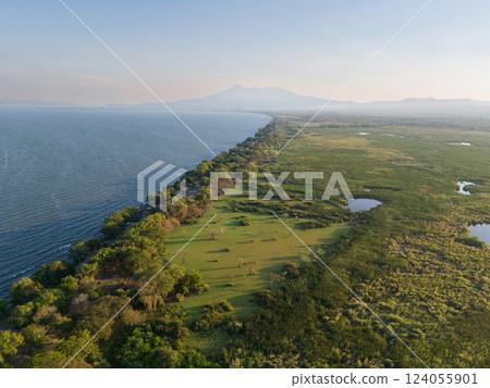 Coastal landscape with lush vegetation along tranquil shoreline at sunset 124055901
