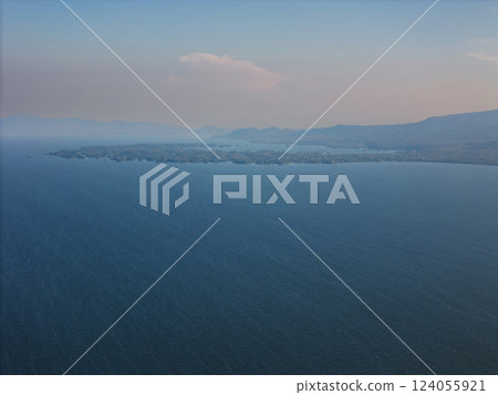 Ethereal view of tranquil waters and distant hills during twilight in serene landscape 124055921
