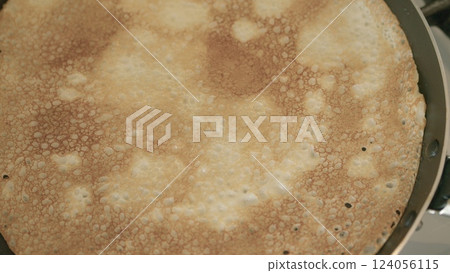 Golden brown crepes cooking beautifully on a hot pan, ready to delight taste buds soon 124056115