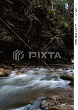 This image captures a fast-flowing river rushing over a rocky bed, creating whitewater rapids. This image captures a fast-flowing river rushing over a rocky bed, creating whitewater rapids. 124056553