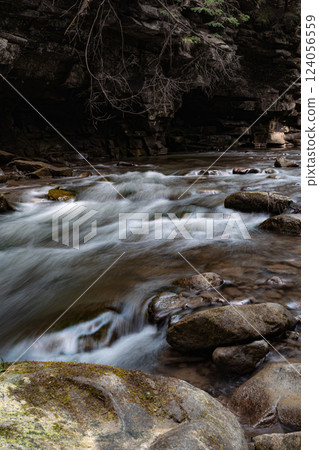 This image captures a fast-flowing river rushing over a rocky bed, creating whitewater rapids. This image captures a fast-flowing river rushing over a rocky bed, creating whitewater rapids. 124056559