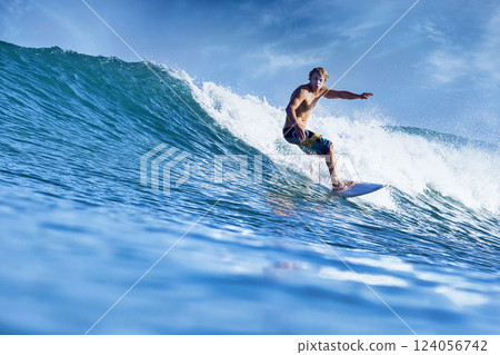 Male surfer on a blue wave 124056742