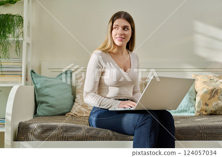Young woman working at home, sitting on couch using laptop 124057034