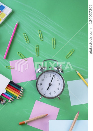 Back to school concept. School supplies and alarm clock on green background, with copy space, top view. Back to school concept. School supplies and alarm clock on green background, with copy space, top view. 124057203