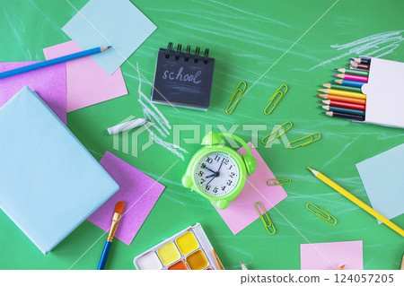 Back to school concept. School supplies and alarm clock on green background, with copy space, top view. 124057205
