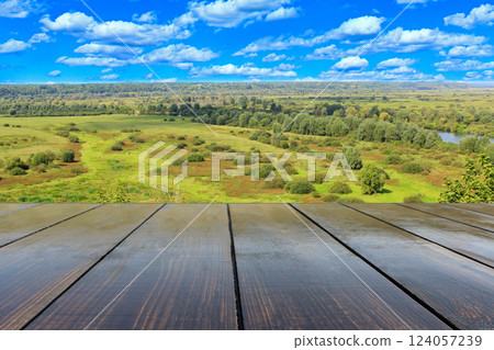 Wood board table in front of summer landscape. Sunny day with wooden vintage boards Wood board table in front of summer landscape. Sunny day with wooden vintage boards 124057239